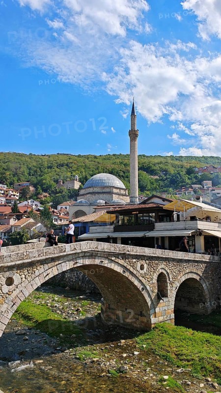 View of a bridge across a river, Prizren Bistrica with mosque in the background and wooded hills, Prizren, Kosovo