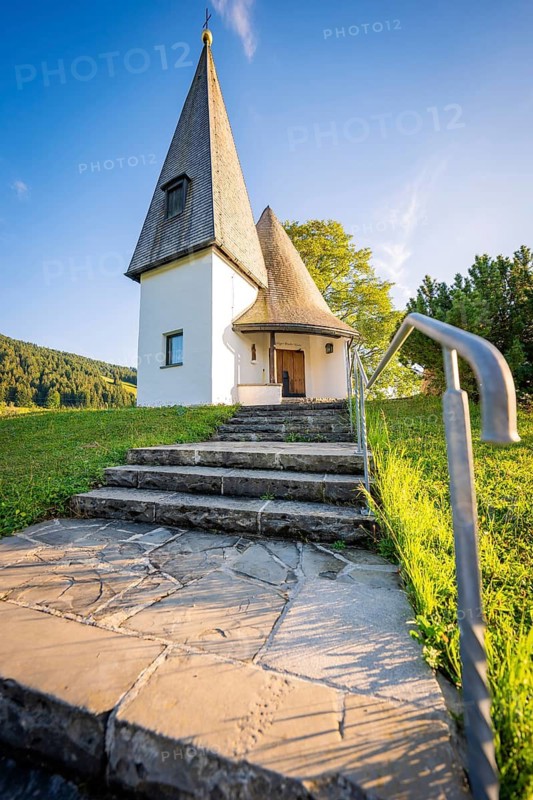 Stone staircase leads to the white-painted chapel on a green meadow in sunny weather, Bruder Klaus Kapelle, Allgäu, Bavaria, Germany