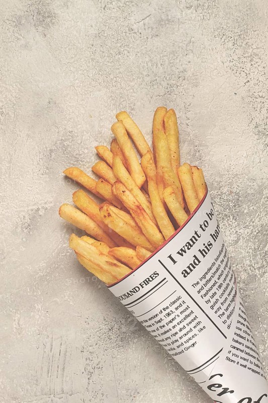 Fried French fries in a paper bag, on an abstract background, without people, in a rustic style, in a cone package, newspaper, a bag from the newspaper