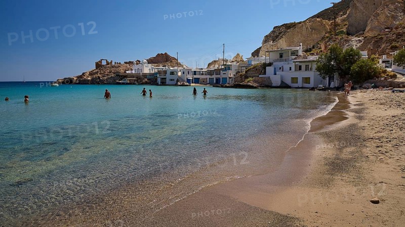 People bathe in clear water on a sandy beach with white buildings and a rocky bay, Palio Ergostasio Kaolini, Old Kaolin Loading Station, Ruins, Firopotamos, Fishing Village, North Coast, Beach, North Coast, Milos, Cyclades, Greek Islands, Greece