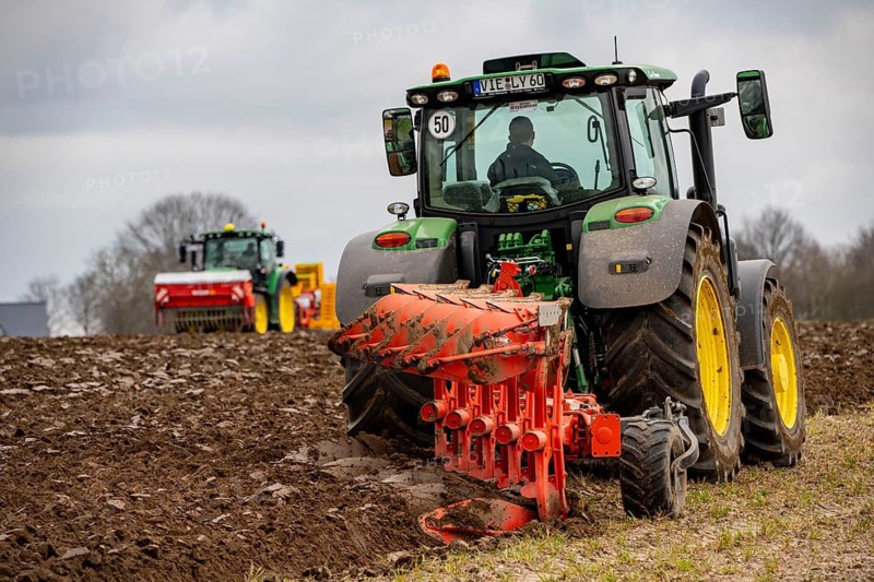 Tractor with a plough preparing the soil of a field for planting, Agriculture, Spring