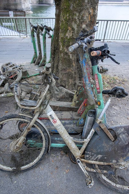 Heavily silted e-bikes and e-scooters recovered from the Rhine show the consequences of improper disposal and the impact on the environment and water, the recovered vehicles were secured on the shore and prepared for proper disposal, Cologne, North Rhine-Westphalia, Germany