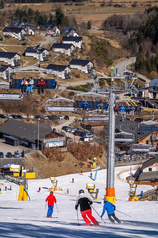 Winter sports area in the Sauerland, Winterberg ski lift carousel, artificial snow slopes, artificial snow from over 360 snow guns, Poppenberg ski area, background holiday homes at Landal Ferienpark Winterberg, 12 of 24 lifts are in operation in mid-March, the rest of the landscape is snow-free, North Rhine-Westphalia, Germany