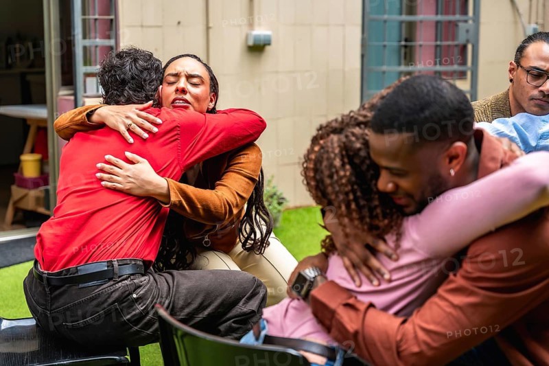 Diverse adults participate in a group therapy session. Embracing and comforting each other in a deeply emotional moment. Showing connection. Empathy. And healing within a supportive community setting