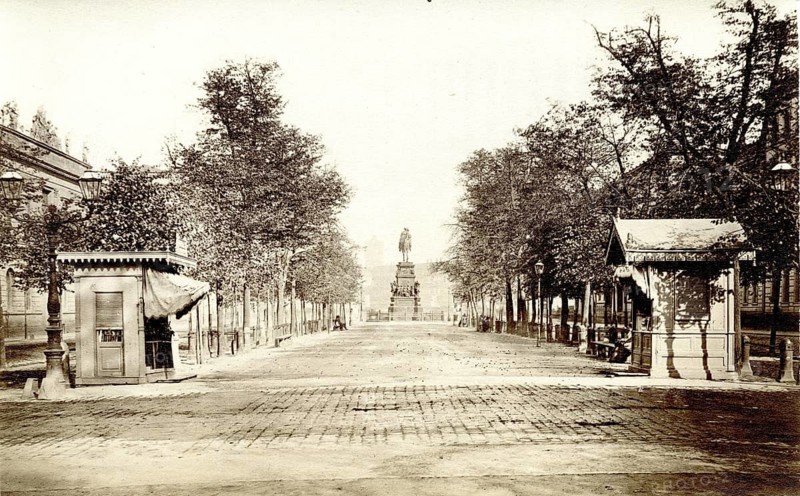 Unter den Linden, central strip, view of Friedrich II. Breite Straße, surrounded by trees, with a monument in the background in an urban atmosphere