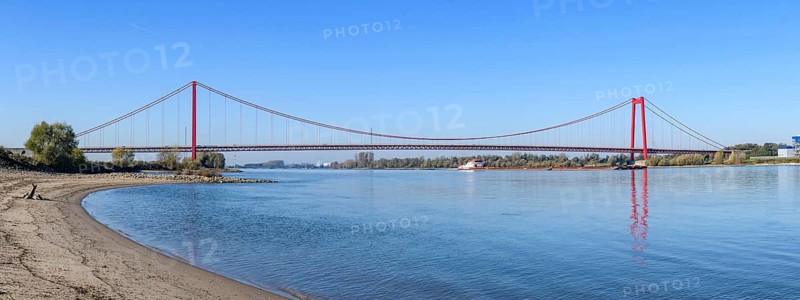 Panorama view from the left bank of the Rhine, western bank of the Rhine, of an earth-anchored suspension bridge with two abutments and red steel piers nicknamed the Golden Gate of the Lower Rhine over the River Rhine, with a total length of 1228 metres the longest suspension bridge in Germany, Emmerich, North Rhine-Westphalia, Germany