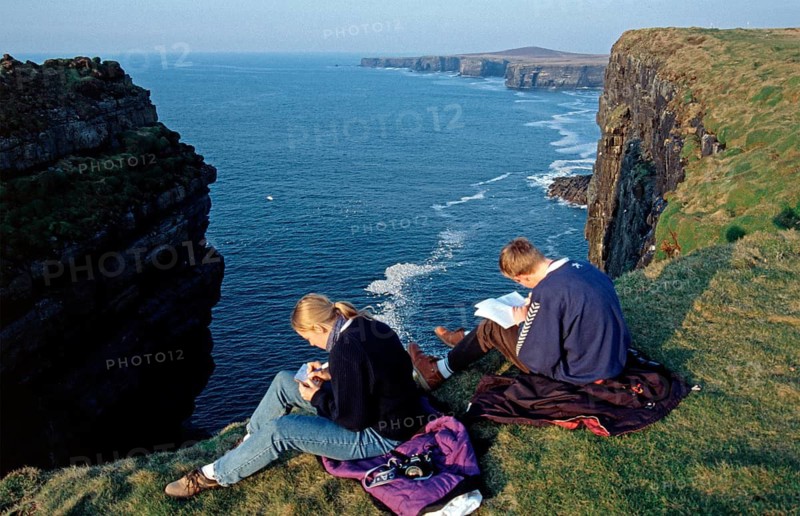Woman and teenager writing postcard and diary, cliffs near Kilkee, County Clare, Republic of Ireland, April 1996, vintage, retro, old, historic