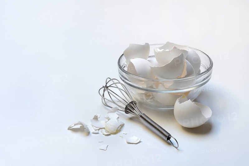 Egg shells in glass bowl and whisk