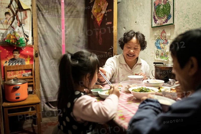 Gao Jian Min (67), Lin Shu Xiang (56) and Gao Xin Rui (5) having dinner, the grandmother bought Nanjing Salt Duck and grilled duck to supplement the dinner, Diao Yu Tai District, Nanjing, China
