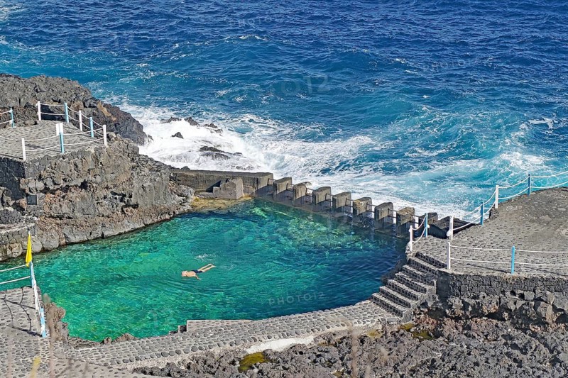 A swimming pool bordered by the sea with clear water on a rocky coast, Charco Azul, San Andres, La Palma, Canary Islands, Spain