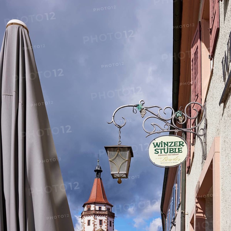 Nose sign of the restaurant and wine bar Winzerstüble, Niggelturm and parasol in rainy weather in Gengenbach, Black Forest, Ortenaukreis, Baden-Württemberg, Germany