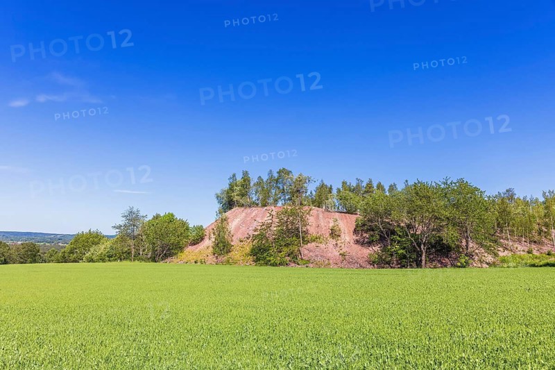 Pile of slag dumps from a Limestone quarry by a lush green field in the countryside, Sweden