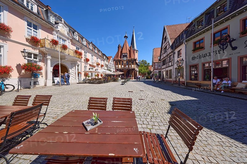 Red tables and chairs of a restaurant and historic town hall on the market square in Michelstadt, Odenwald, Odenwaldkreis, Hesse, Germany