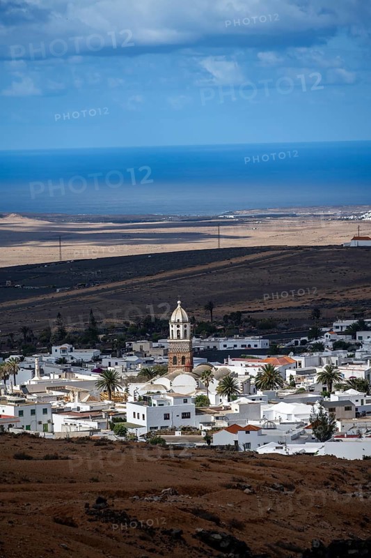 View of town, white houses of Teguise with church tower in dry volcanic landscape, Lanzarote, Canary Islands, Spain