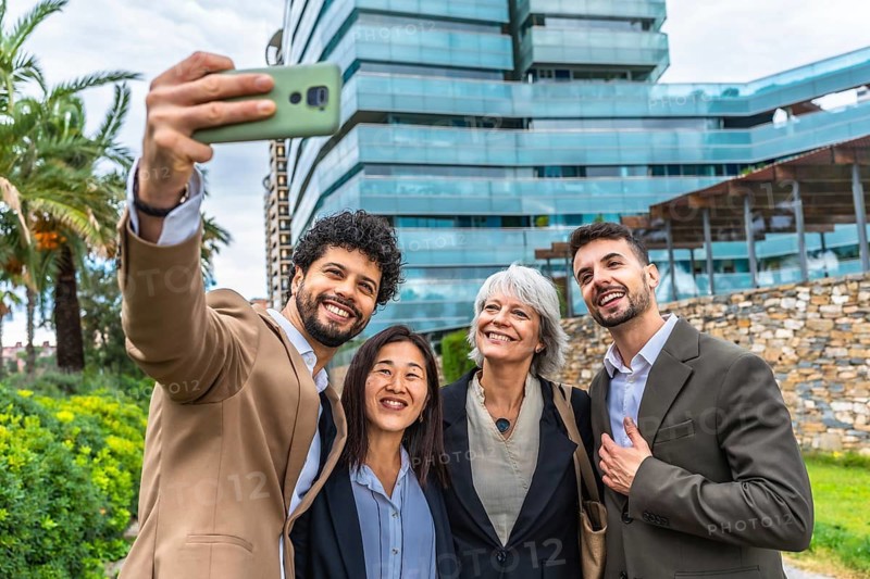 Diverse group of business people taking selfie outside a financial building in a tropical city