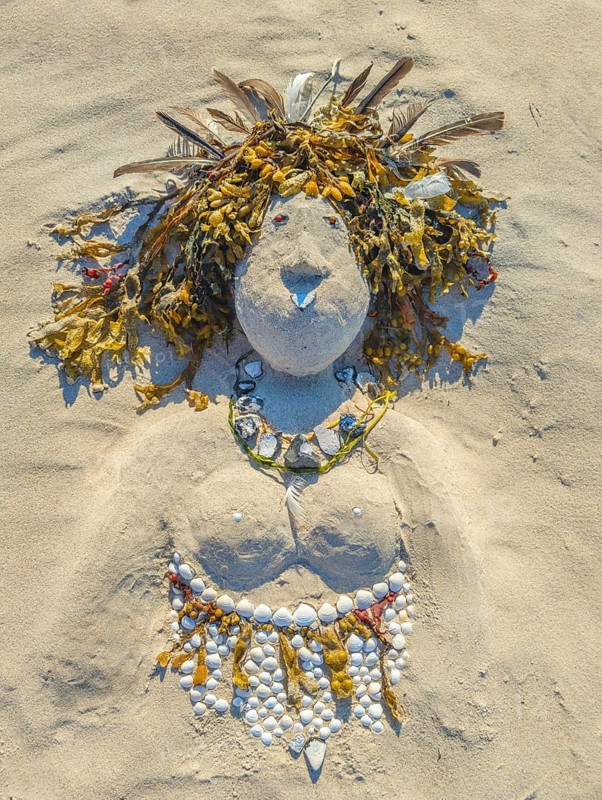Art on the beach woman portrait made of sand shells tank feathers