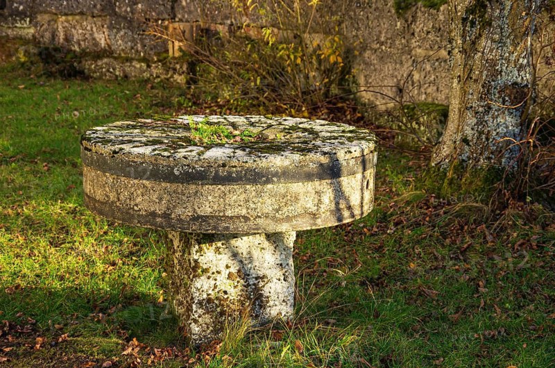 Historic millstone, set up like a table in the desert cemetery of the village and today the ghost town of Gruorn on the former military training ground in the Münsingen estate district, Baden-Württemberg, Germany. A Historic Millstone, Set Up Like a Table in the Churchyard of the Deserted Village of Gruorn — Now a Ghost Place — Located on the Former Military Training Area on Munsingen Estate, Baden-Württemberg, Germany