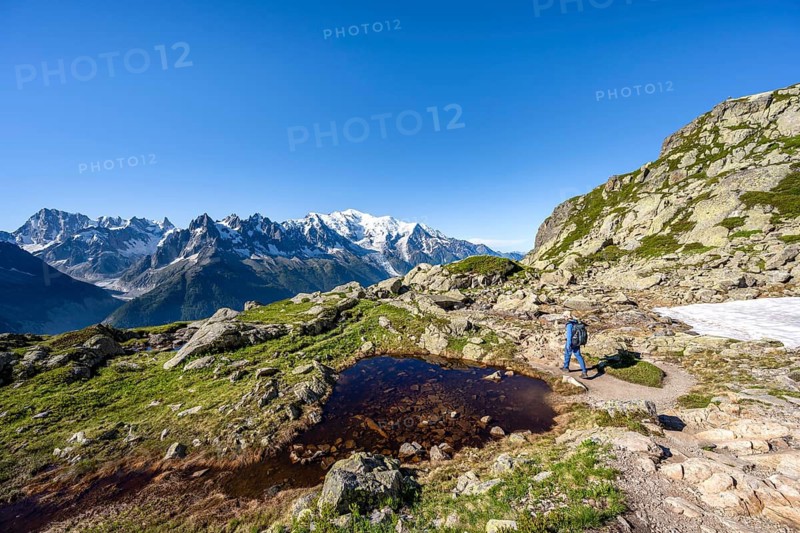 Mountaineer in mountain landscape with small lake, mountain panorama of the Mont Blanc massif with glaciated summit of Mont Blanc, Aiguilles Rouges, Chamonix-Mont-Blanc, Haute-Savoie, France