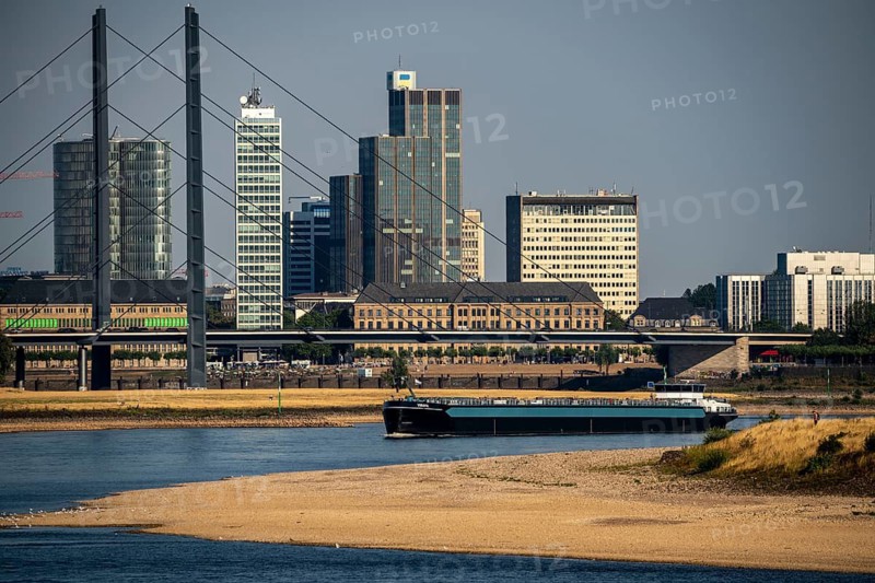 Rhine at Düsseldorf, extremely low water, Rhine level at 47 cm, falling, barge in front of the skyline with the Rheinkneibrücke bridge, sandbanks, freighters are only allowed to sail with very reduced cargo and very slowly, North Rhine-Westphalia, Germany