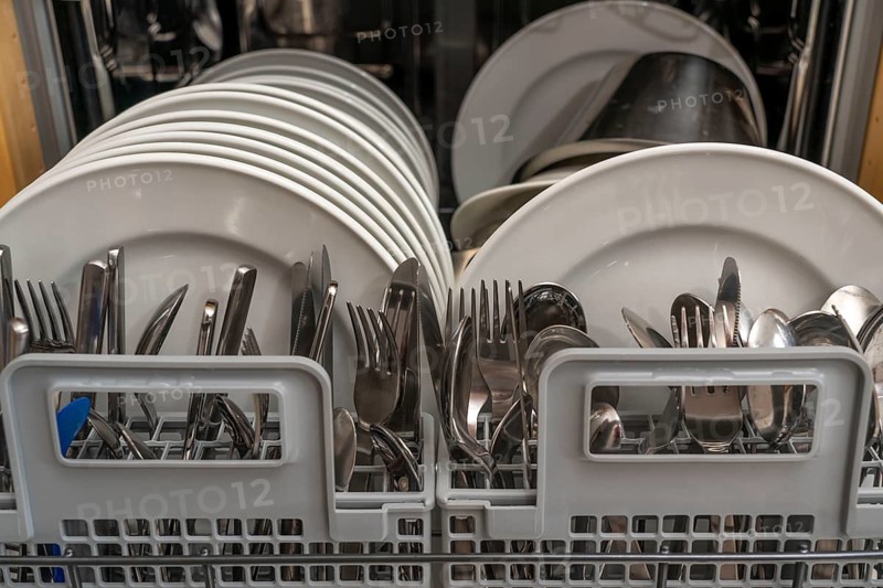 Dishwasher, full, with cleaned crockery, cutlery, cooking utensils