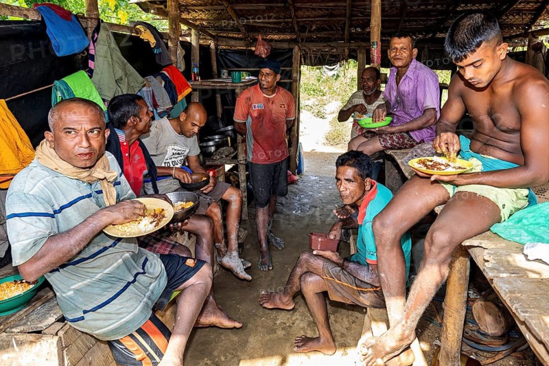 Several men take a break for dinner in a simple hut and enjoy community, the sapphire and gemstone mines near Ratnapura in Sri Lanka