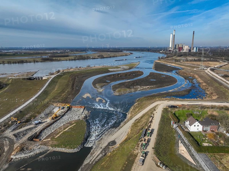 Dinslaken, Voerde, North Rhine-Westphalia, Germany - New Emscher estuary into the Rhine. Renaturalisation of the Emscher. Flood protection through land expansion. The decommissioned STEAG Voerde coal-fired power station in the background. The mouth of the Emscher into the Rhine was moved almost 500 metres north from Dinslaken to Voerde. Fish can now swim barrier-free up the new Emscher from the Rhine through a newly created floodplain area. Following the construction of a parallel sewer, the Emscher has been completely free of sewage since January 2022. The river was previously an open, above-ground combined sewer with rainwater and wastewater. Emscher estuary courtyard on the right