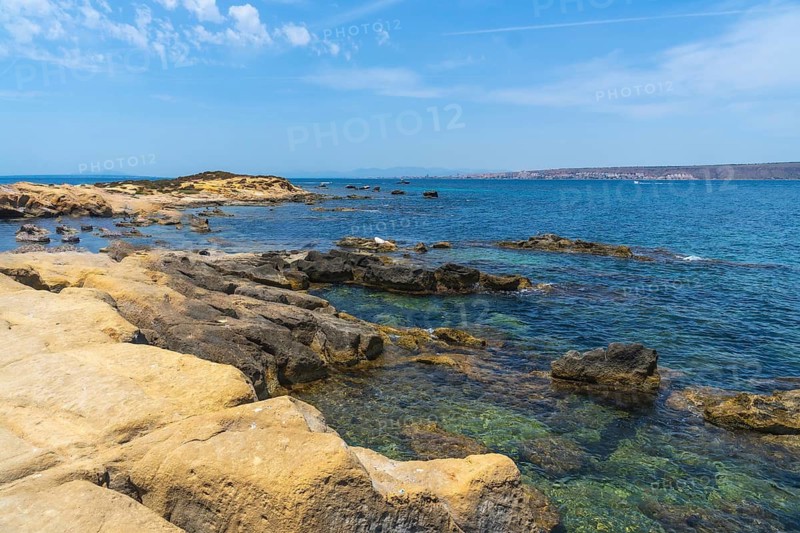 Tabarca island showcasing its rugged rocky coastline and transparent mediterranean waters under a bright blue summer sky, offering an ideal setting for vacation exploration and nature enjoyment