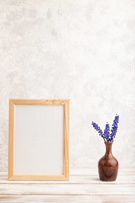 Wooden frame with blue muscari hyacinth flowers in ceramic vase on gray concrete background. side view, copy space, still life, mockup, template, spring, summer minimalism concept