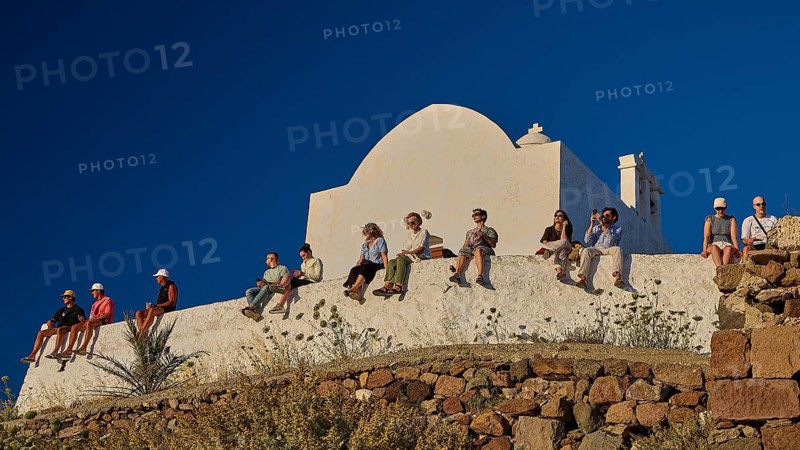 Kastro, Plaka Castle, people sitting on a wall in front of a white church under a clear blue sky, Plaka, main town on Milos, island of Milos, volcanic island, Cyclades, Greek islands, Greece