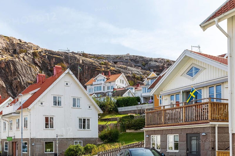Typical wooden houses in front of the steep rock face of the Vetteberg in Fjällbacka, Västra Götalands län, Sweden