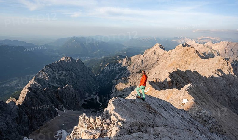 Mountaineer on a steep rocky ridge, impressive mountain landscape, view of the Höllental and the Alpspitze from the Jubiläumsgrat, in the evening light Zugspitze, Wetterstein range, Bavaria, Germany
