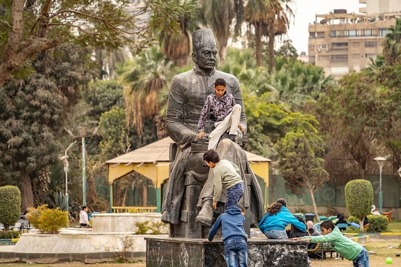 Children climb on the statue of poet Hafez Ibrahim in Al Horreya Garden park in Cairo, Egypt