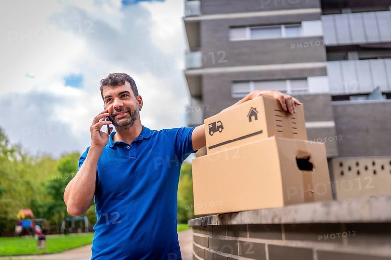 Delivery man talking to the mobile standing next to boxes outdoors in the city