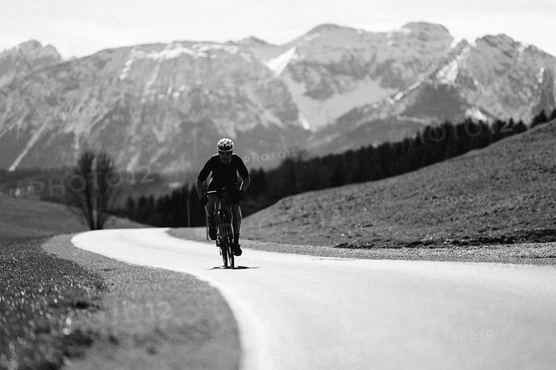 Road bike rider in spring near Halblech in the Allgäu in front of a picturesque backdrop of the Alps, Bavaria, Germany