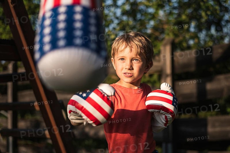 Cute boy boxing bag in the garden during sunny afternoon