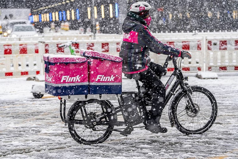 Winter weather, heavy snowfall, city centre traffic, courier of the delivery service Flink on bicycle in the snow, Essen, North Rhine-Westphalia, Germany