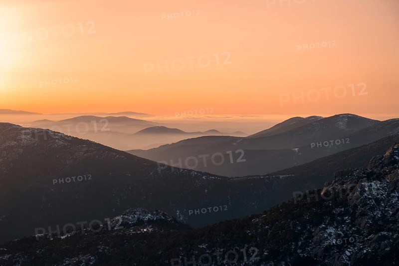 Capture of a serene, snow-dusted landscape at Siete Picos in Guadarrama Mountains, Madrid. The early morning light casts a warm glow over the snowy peaks and valleys