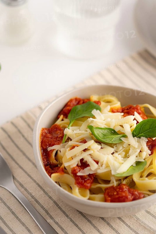 A cozy bowl of spaghetti topped with rich tomato sauce, fresh spinach leaves, and grated parmesan cheese. Perfect for a comforting Italian meal