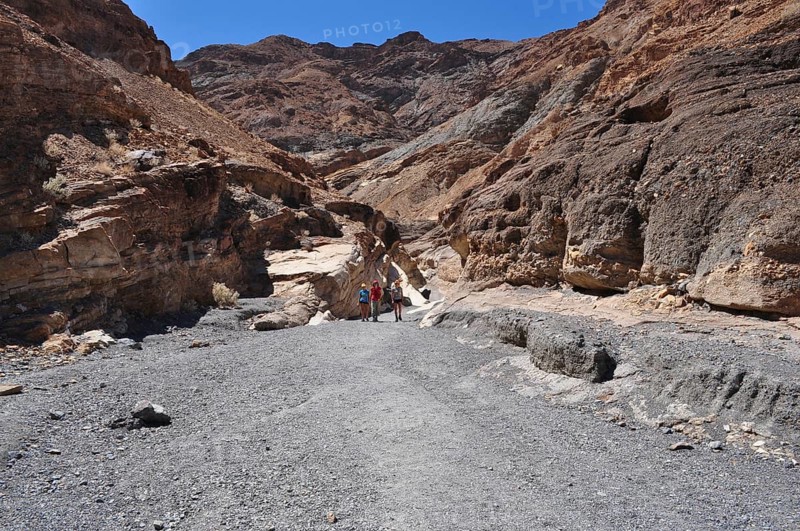 People in a wide rocky gorge under bright blue sky, Death Valley National Park, Mojave Desert, California, Nevada, USA