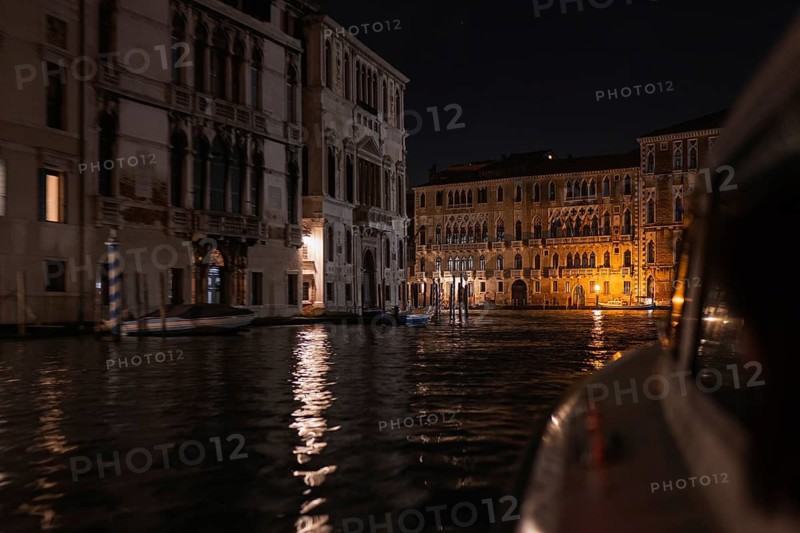 The enchanting beauty of Venetian architecture as the illuminated facades reflect on the serene waters. This captivating night view captures the essence of Venice, Italy