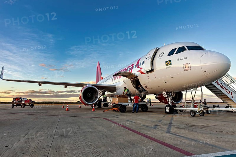 Passenger plane on tarmac, people preparing it for flight as the sun sets, airplanes on the runway at Petrolina airport in Brazil