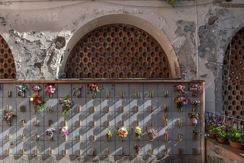 Graves with floral decorations in a courtyard at the Monumental Cemetery, Cimitero monumentale di Staglieno), Genoa, Italy