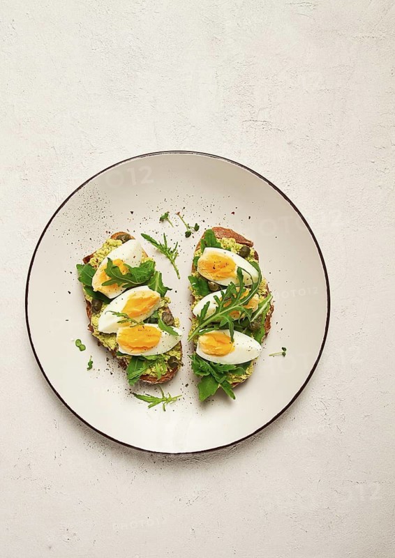 Sandwich with mashed avocado, boiled egg, and arugula, on bread, homemade, breakfast