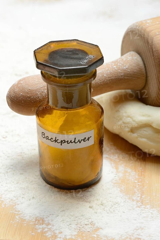 Baking powder in bottles and dough with rolling pin