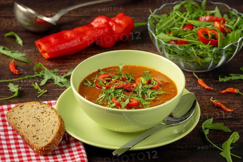 Goulash soup with peppers and arugula in addition to bread, peppers and salad