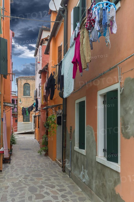 Colourful houses with laundry on the line in an alley on Burano, Venice, Veneto, Italy