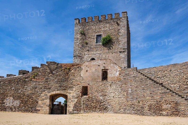 Castle with stone tower and sandy square, overgrown, rugged charm, Monsaraz, Évora, Portugal