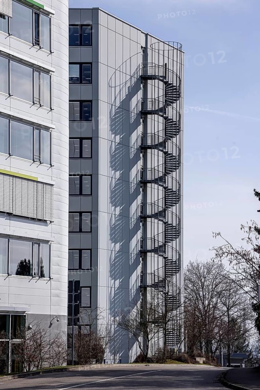 Escape staircase in a building. Spiral staircase with shadows cast on the façade. Stuttgart, Baden-Württemberg, Germany