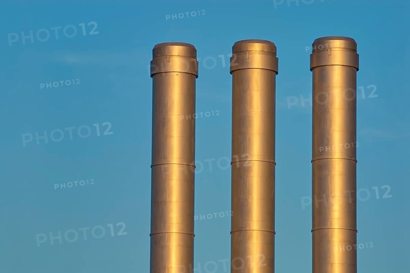 Three golden industrial chimneys in front of a clear blue sky, Würzburg, Mainfranken, Bavaria, Germany