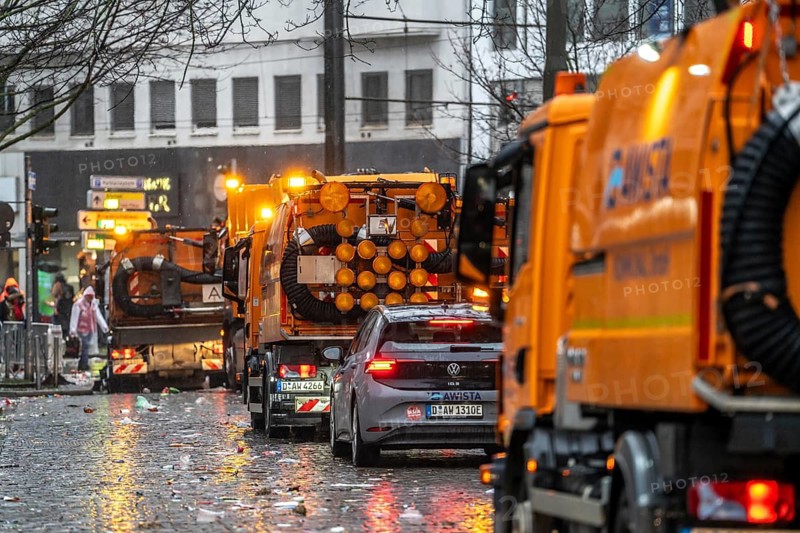 Sweeping on Rose Monday in Düsseldorf, the municipal utilities clean up after the train, confetti, camels, trash, employees with sweepers from AWISTA, Society for Waste Management and City Cleaning, central disposal and urban cleaning companies in Düsseldorf, clean the train's path with their street cleaning machines, North Rhine-Westphalia, Germany